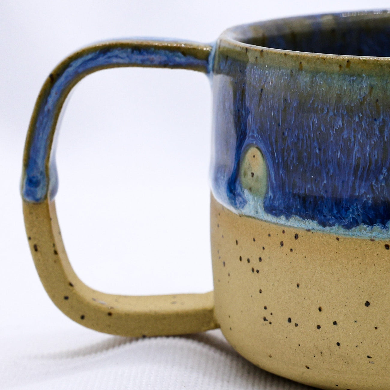 Ceramic mug with blue interior and beige exterior on a white background