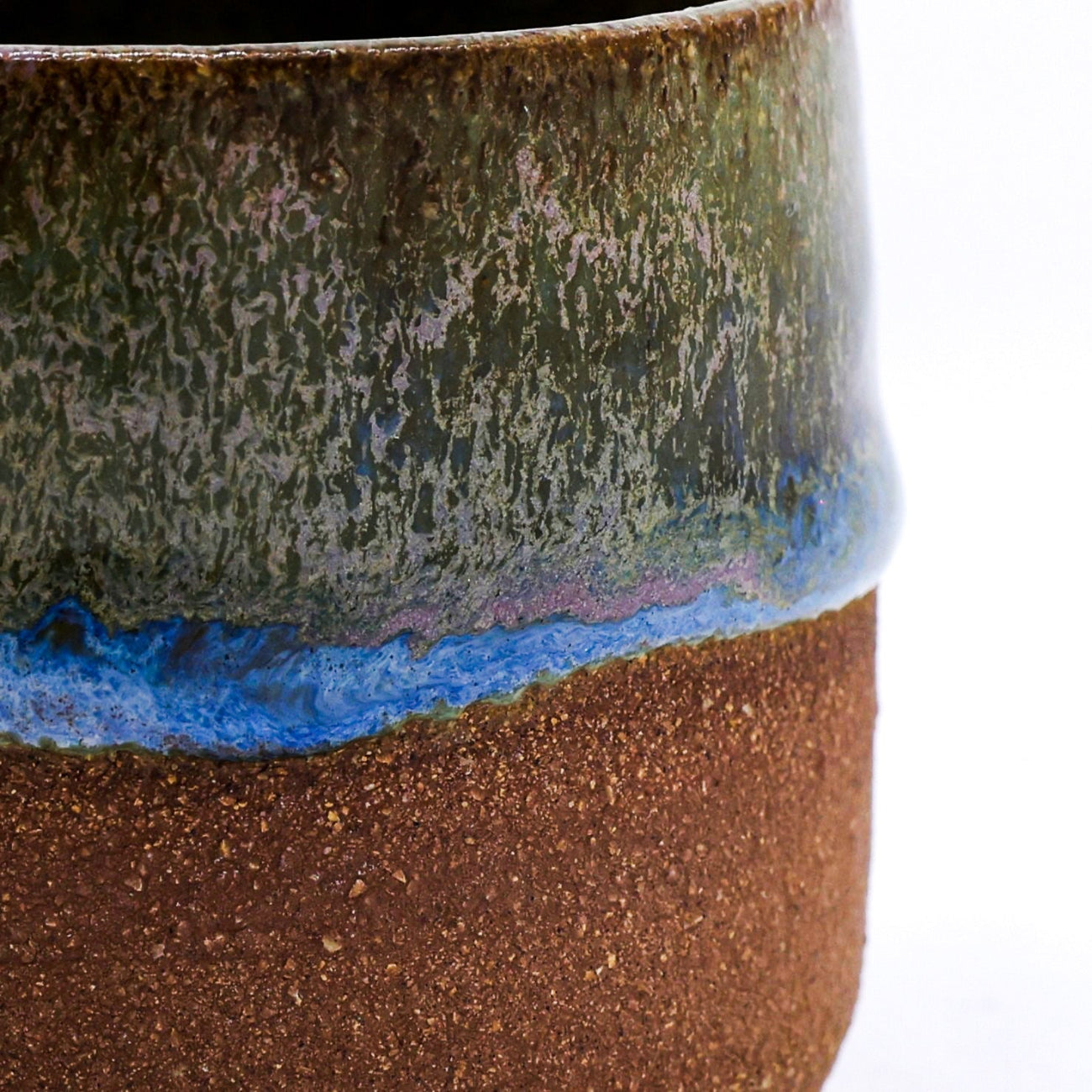 Close-up of a ceramic mug with layered glaze in brown, blue, and green.