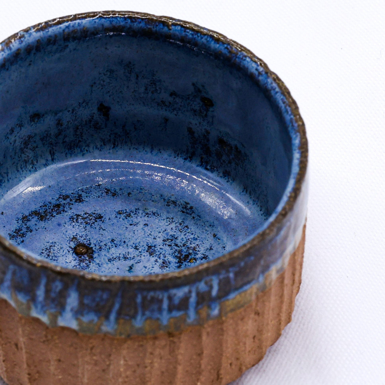 Ceramic bowl with blue interior and brown exterior on a white background