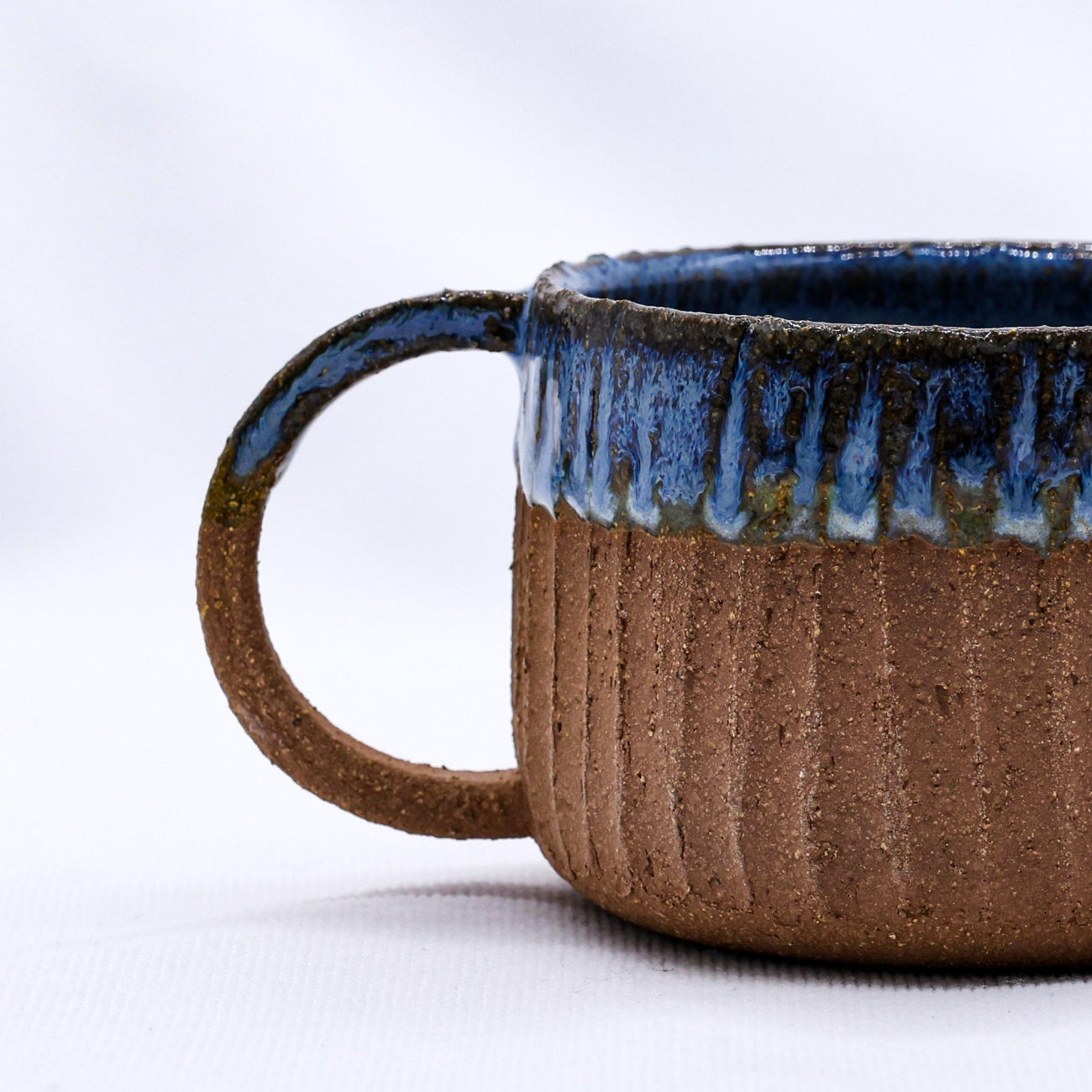Ceramic mug with blue interior and brown exterior on a white background