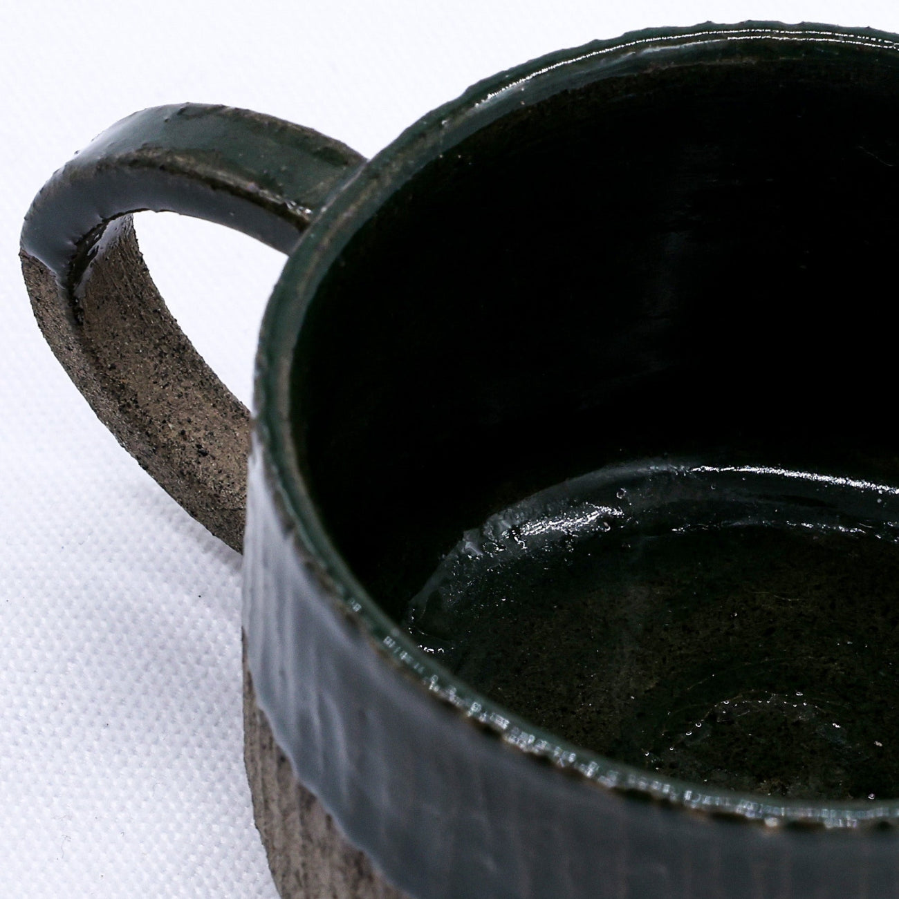 Black ceramic mug with textured handle on a white background