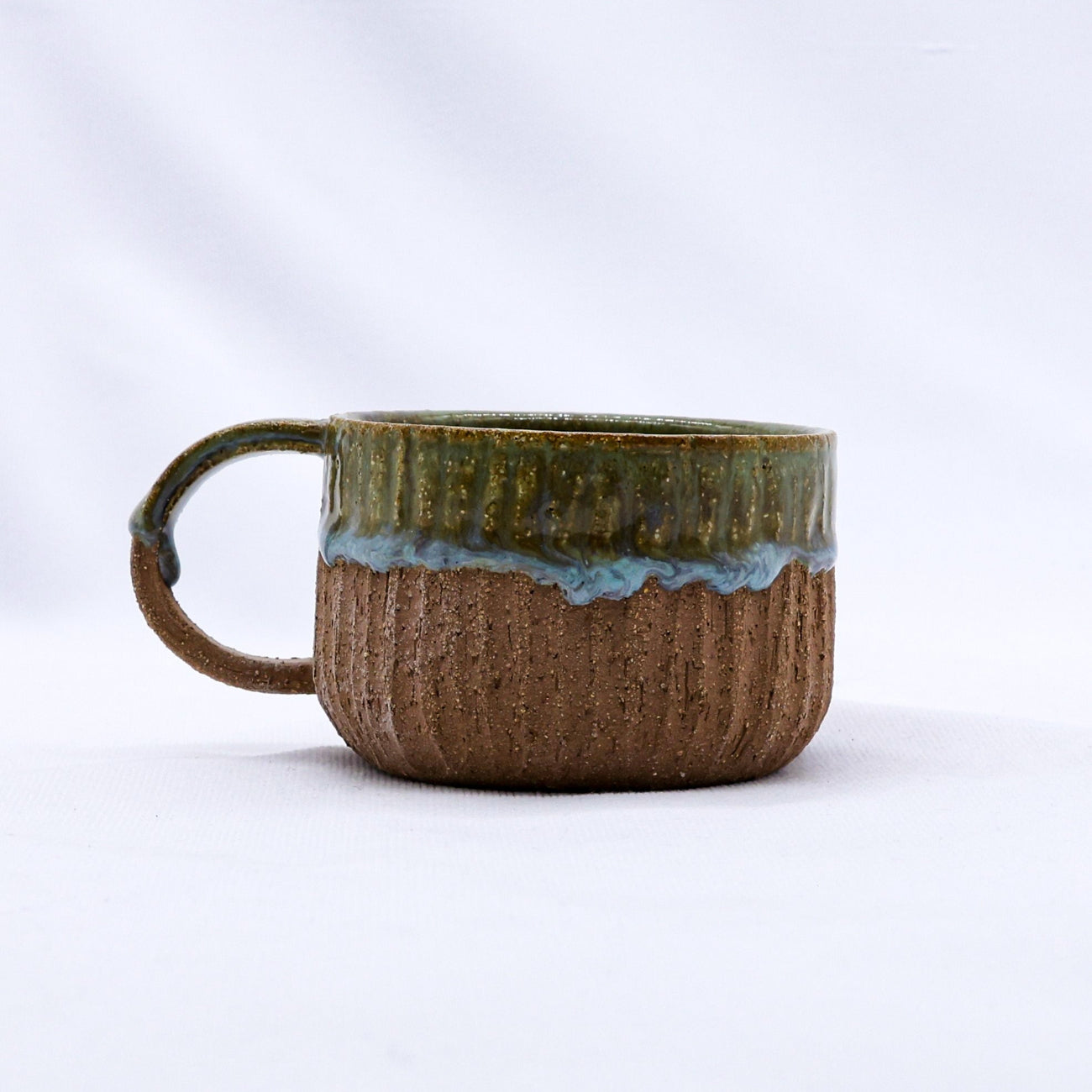 Ceramic mug with textured surface and gradient colour on a white background