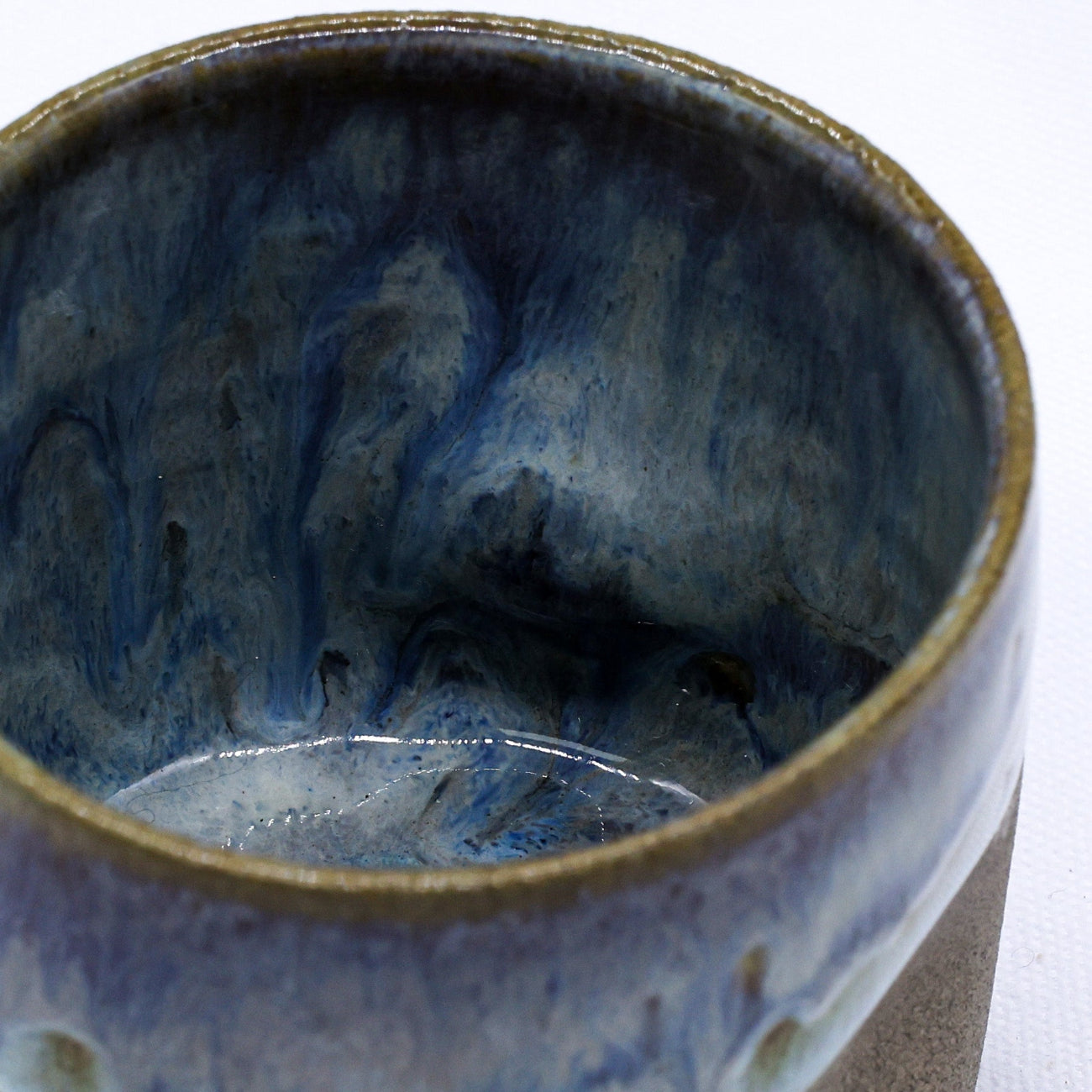 Ceramic cup with blue and brown glaze on a white background