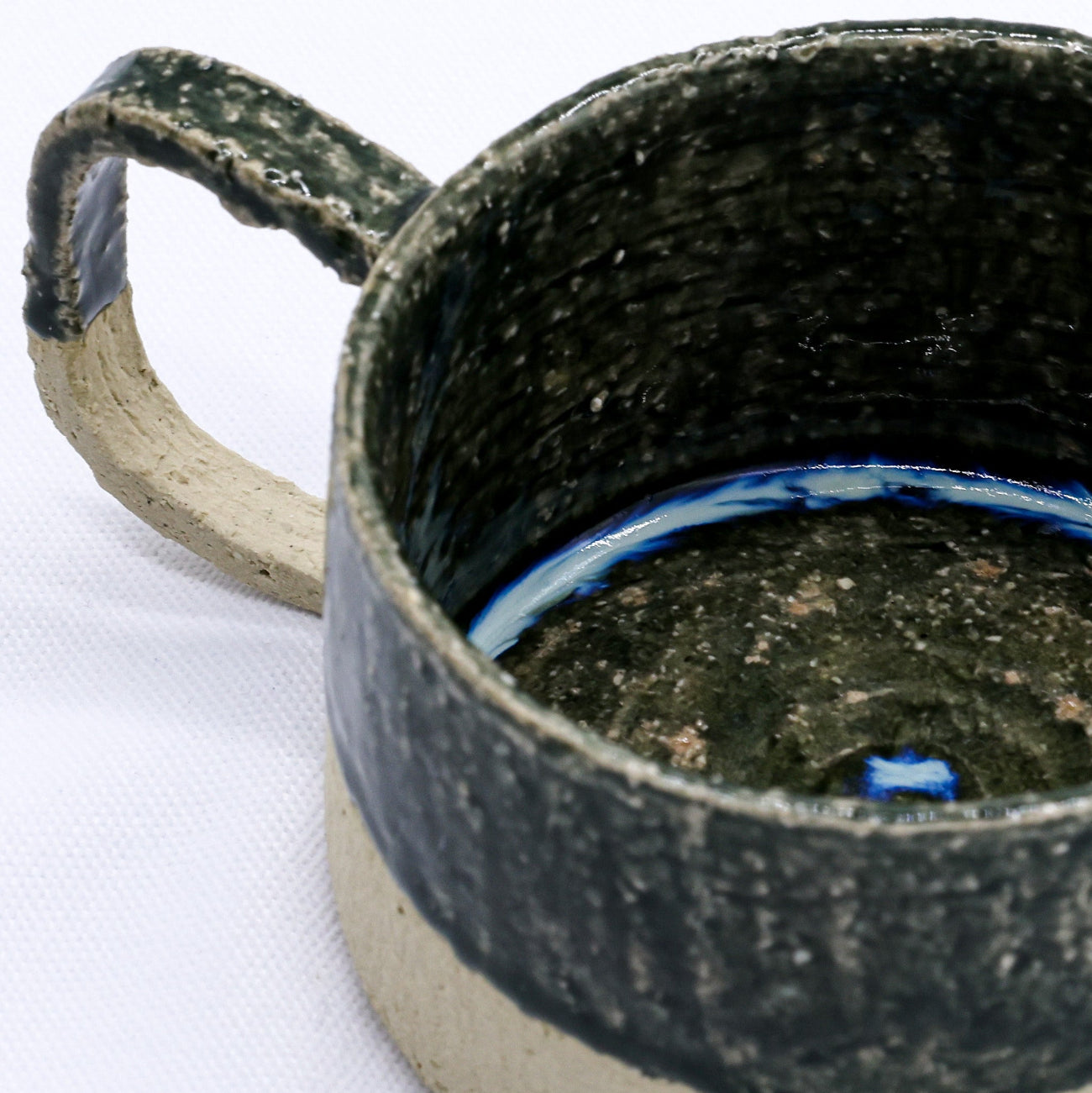 Close-up of a ceramic mug with a textured surface on a white background