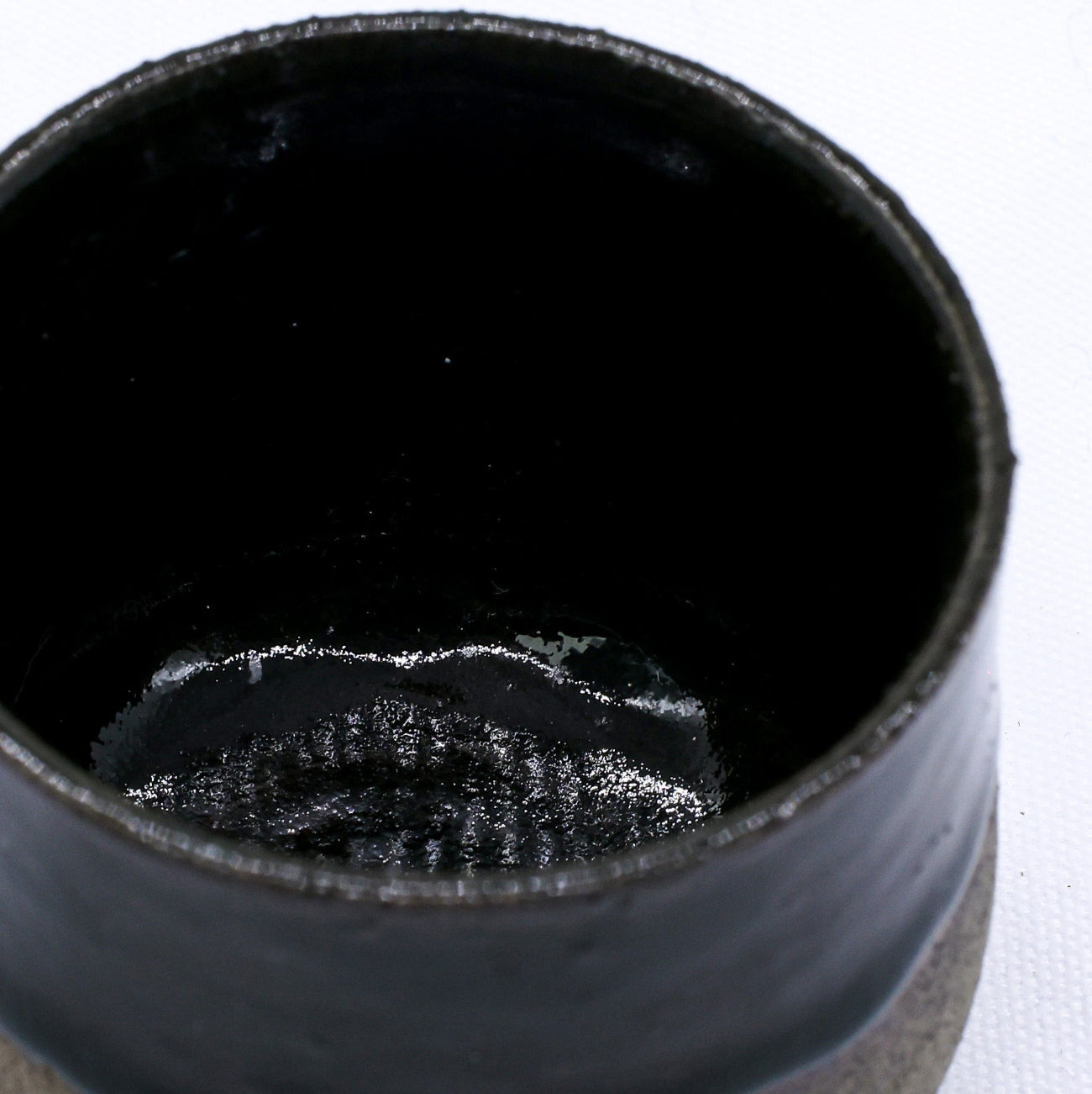 Black ceramic cup with textured interior on a white background