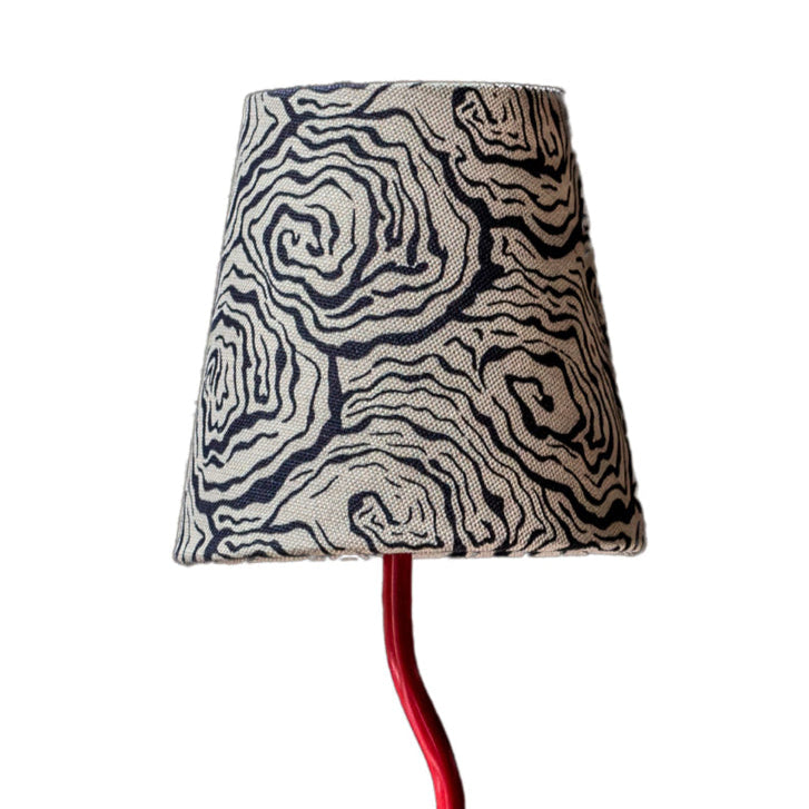 Lamp with a patterned shade and red stand on a white background