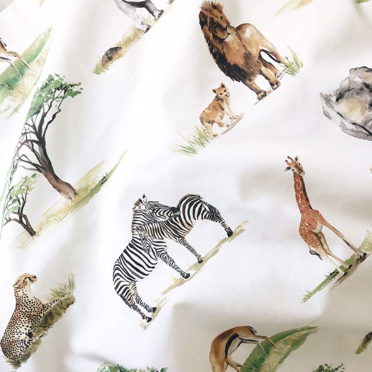 Fabric with safari-themed design featuring animals and trees on a white background