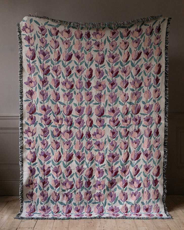 Floral patterned throw blanket on a wooden floor with a dark background