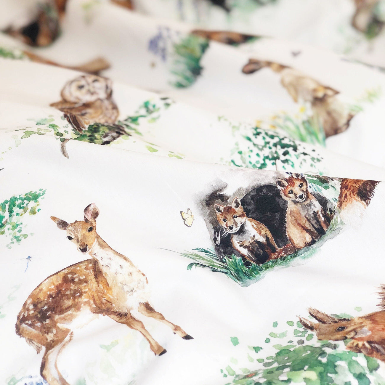 Fabric with animal pattern including deer, fox, and owl on a white background