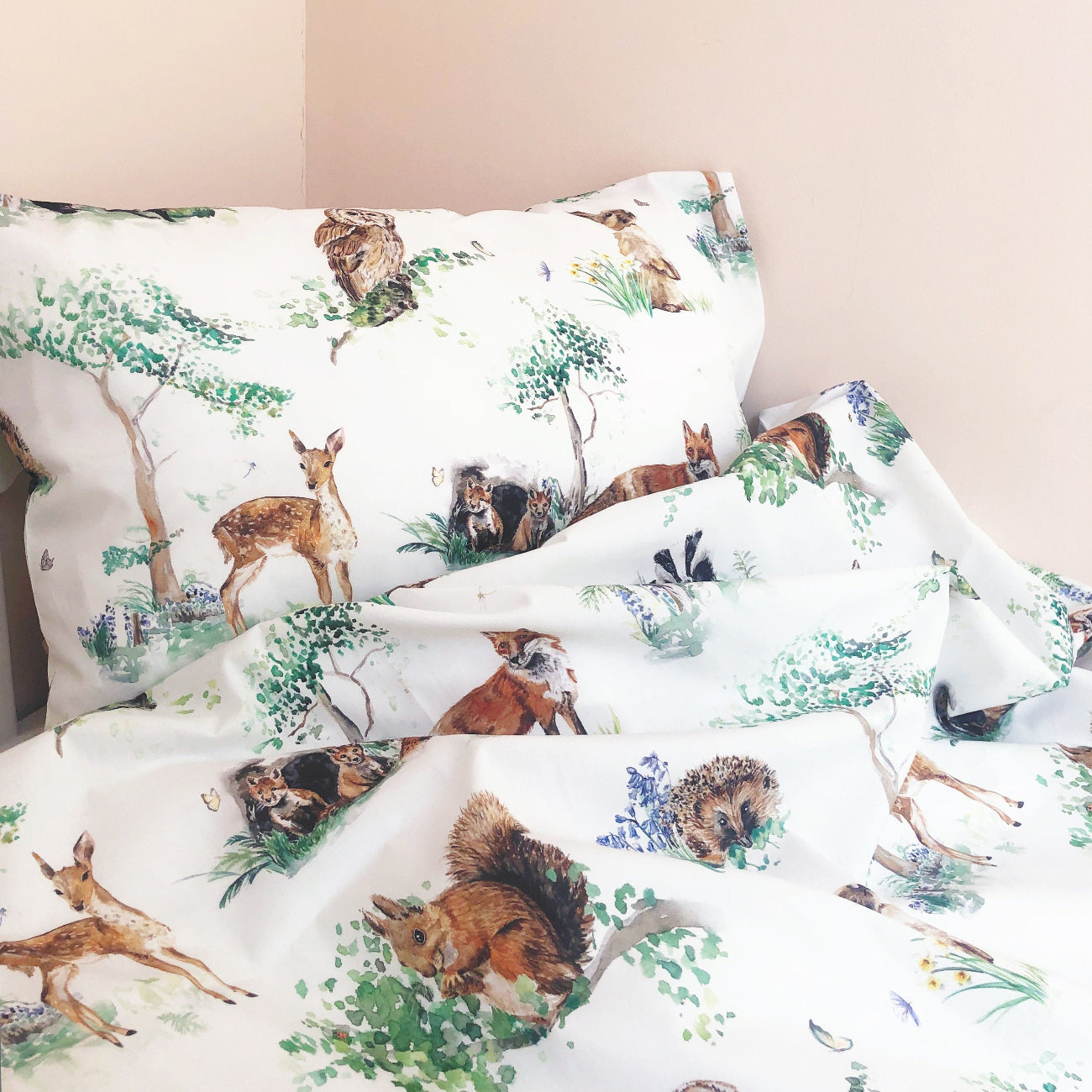 Woodland-themed bedding set with deer, squirrel, and tree design on a white background.