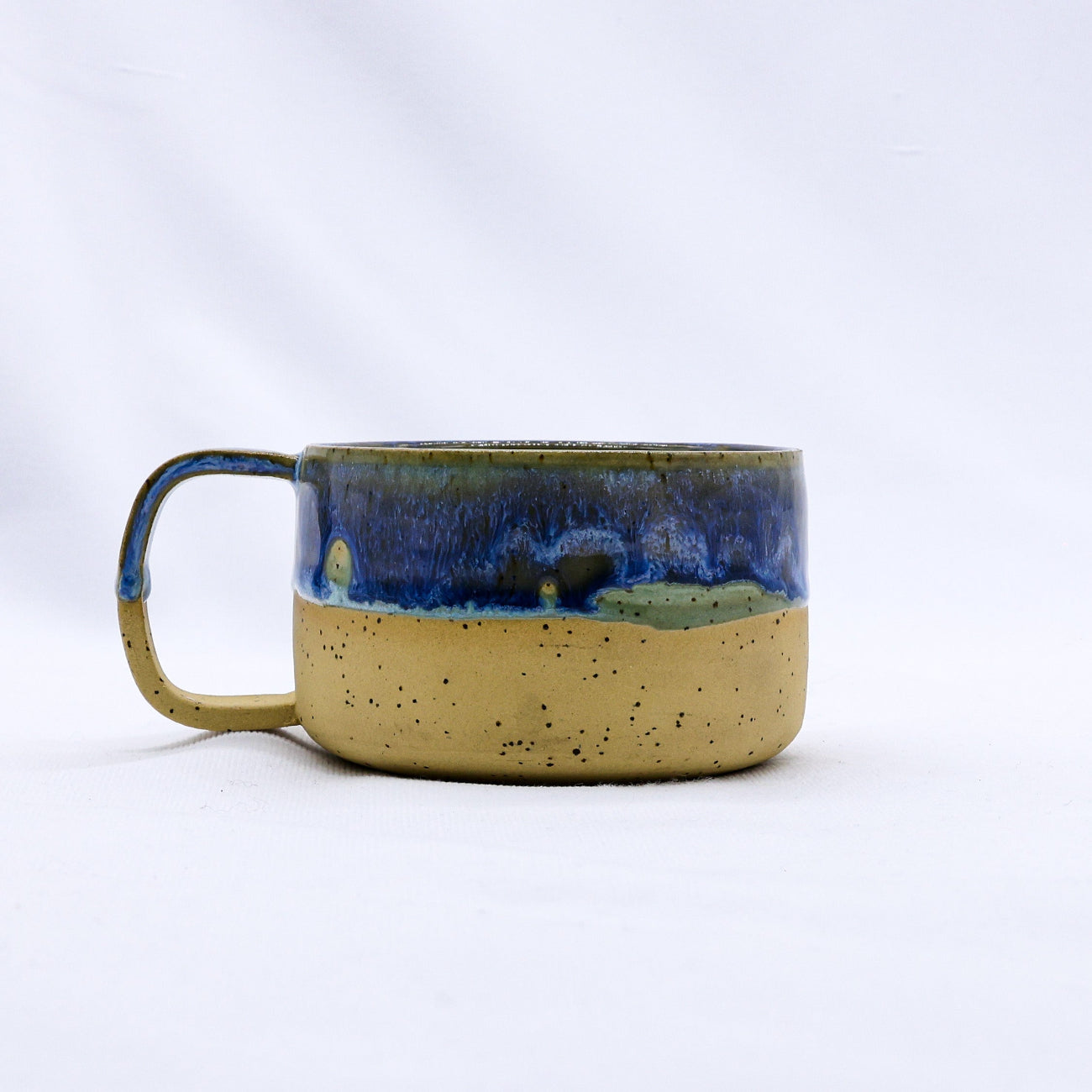 Ceramic mug with blue and beige glaze on a white background