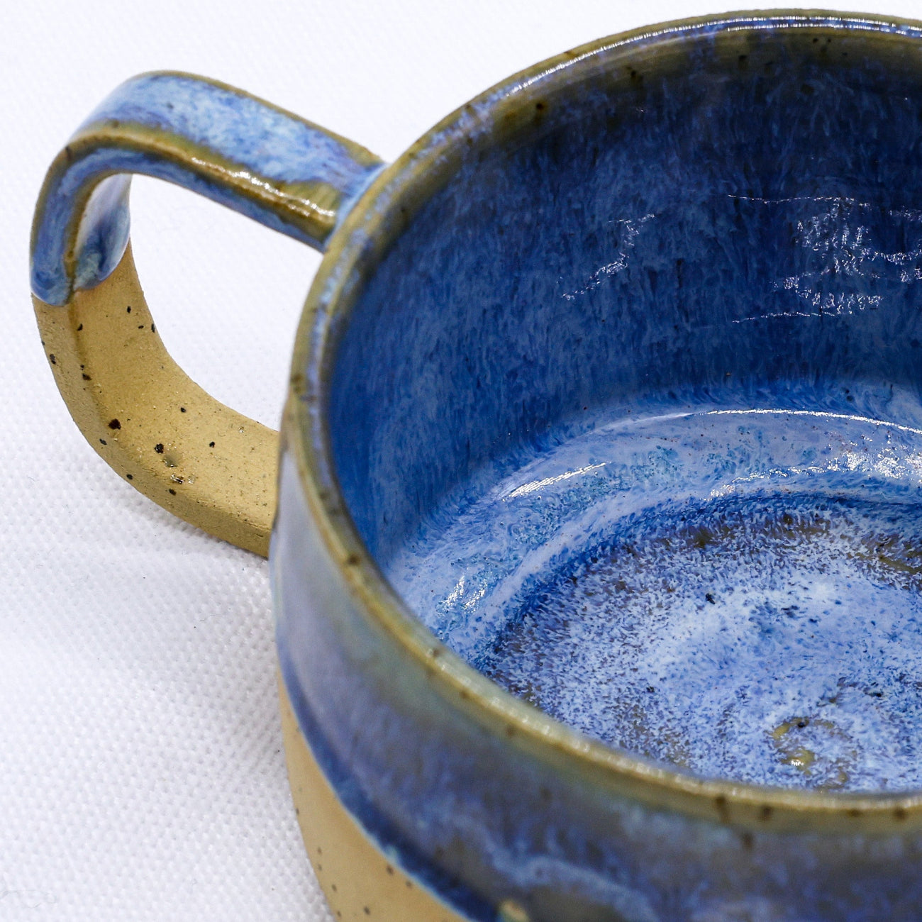 Blue ceramic mug with a speckled texture on a white background