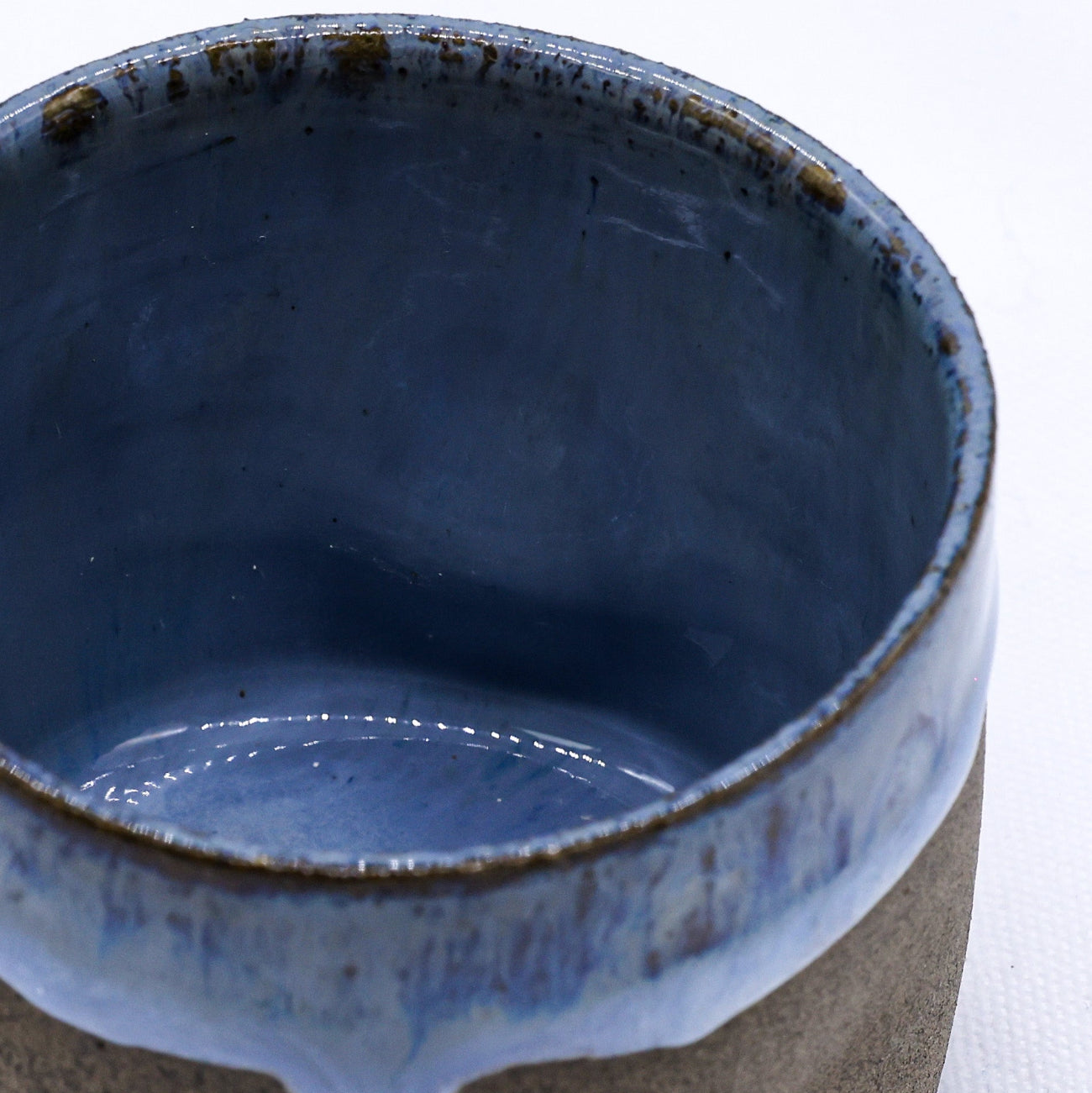 Ceramic cup with blue interior and brown exterior on a white background