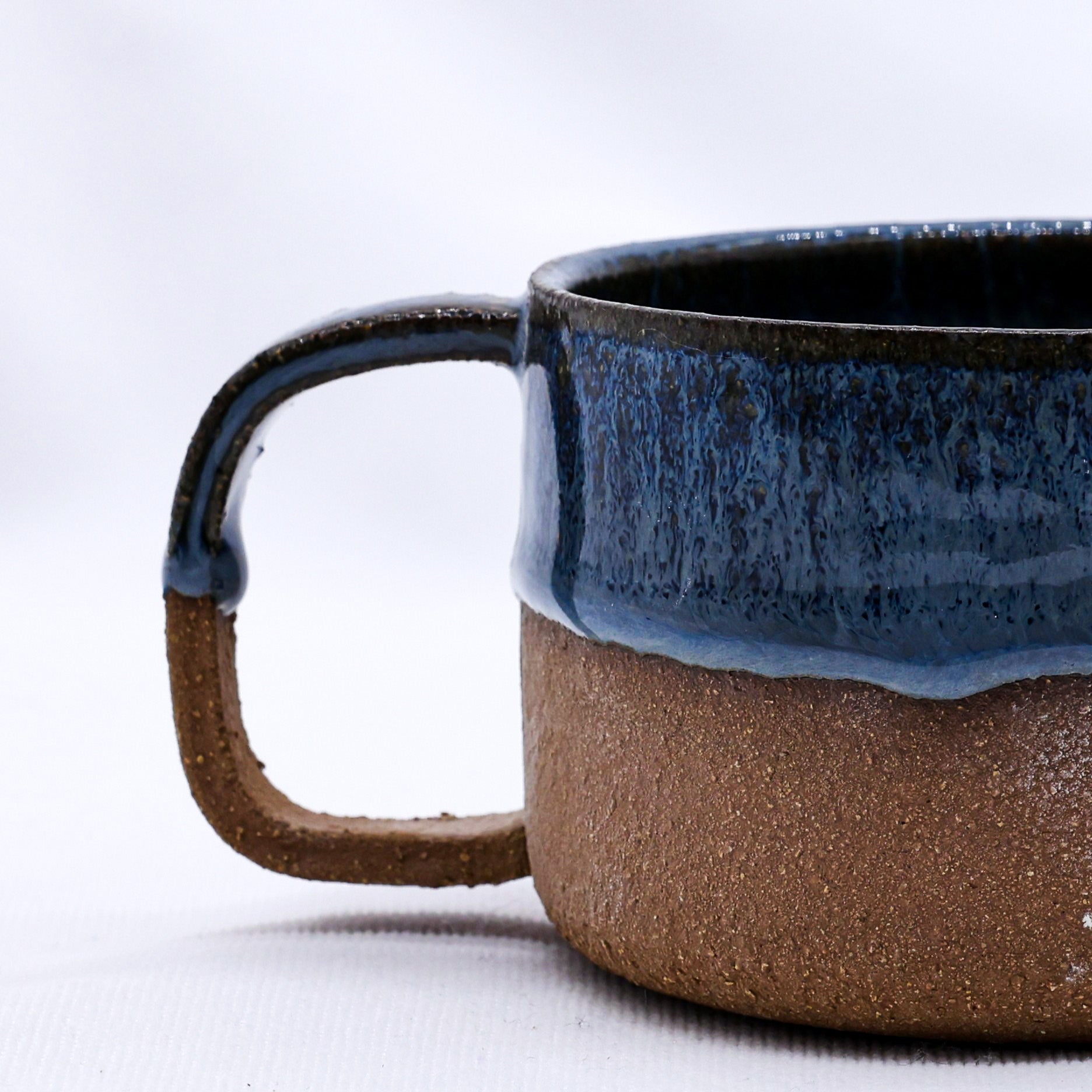 Ceramic mug with blue top and brown bottom on a white background
