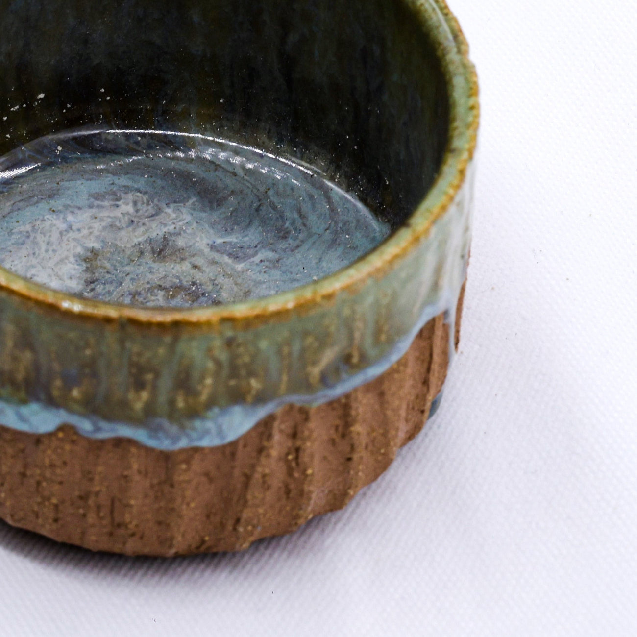 Ceramic mug with textured brown base and blue interior on a white background