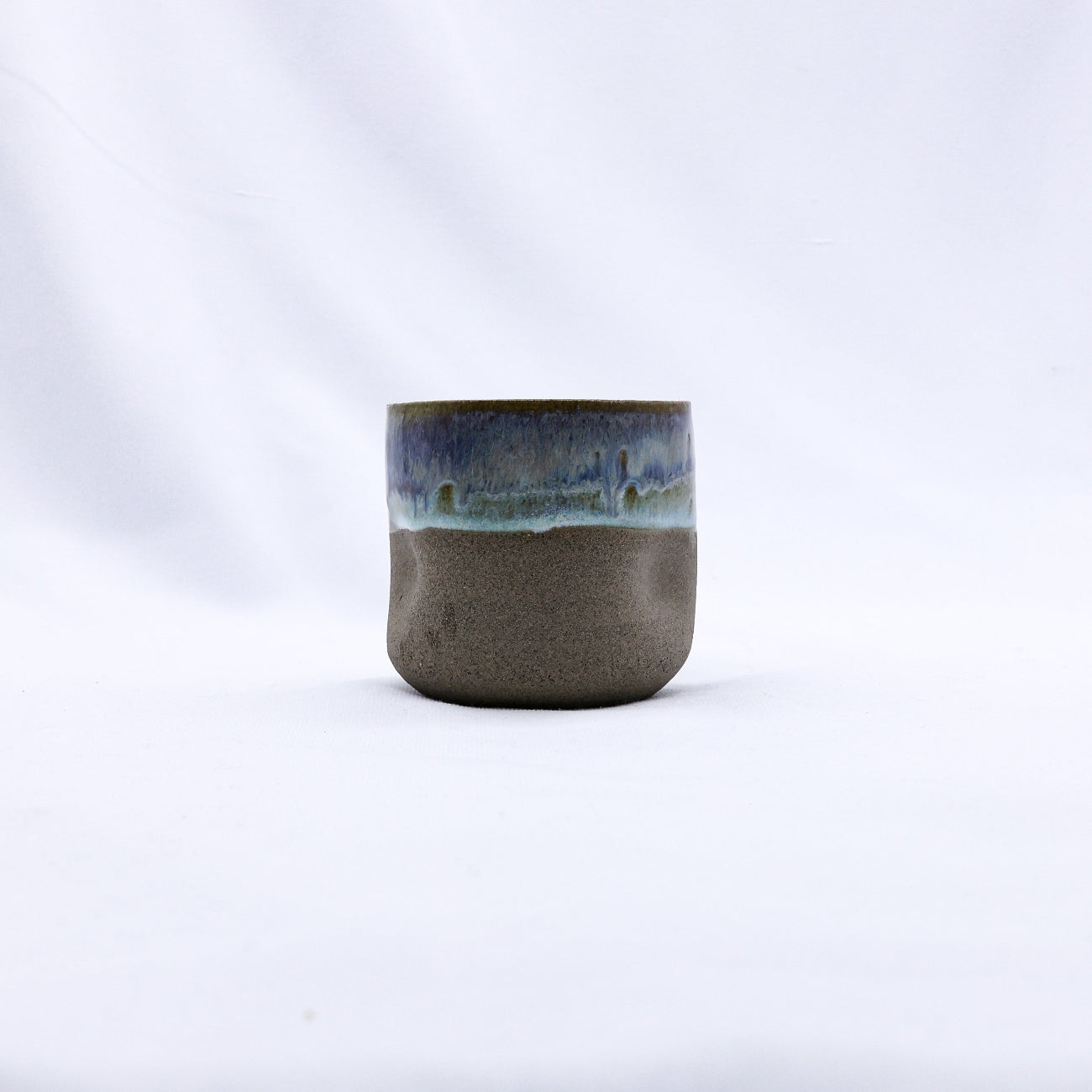 Ceramic cup with two-tone glaze on a white background