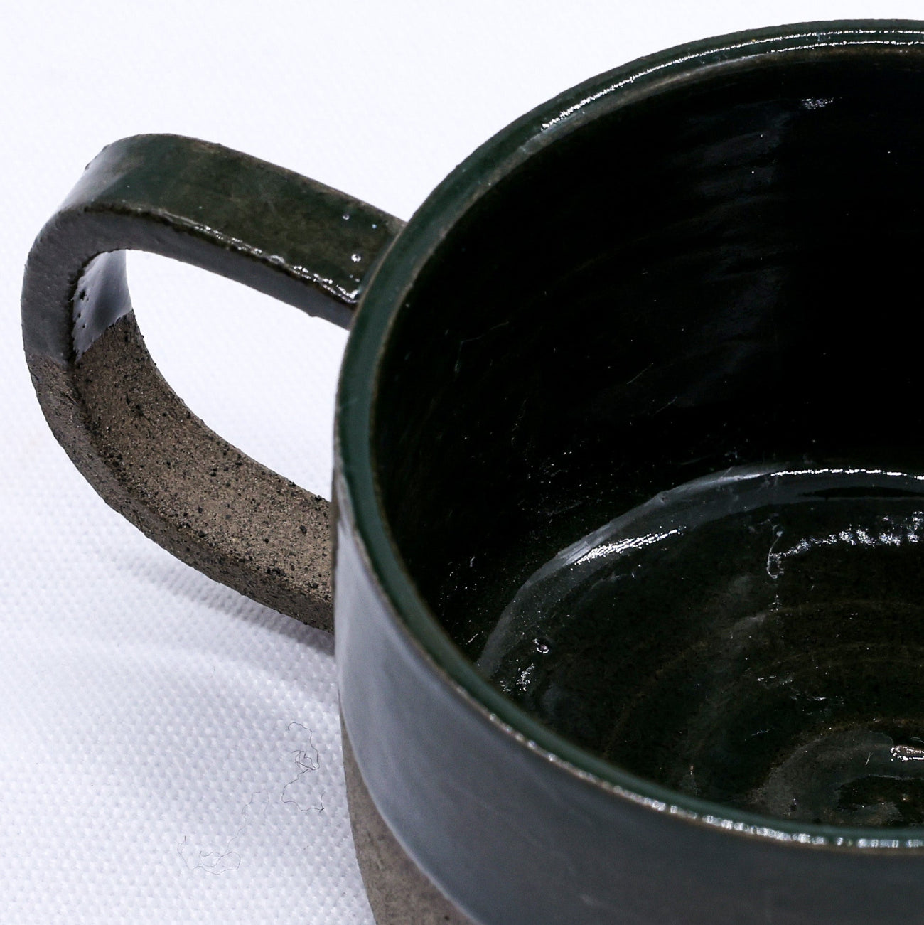 Black ceramic mug with a textured handle on a white background