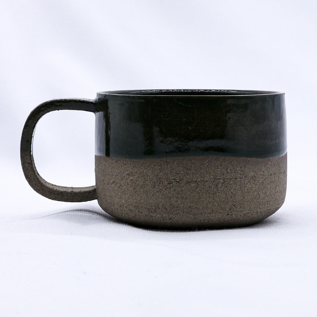 Two-toned ceramic mug with black top and brown bottom on a white background
