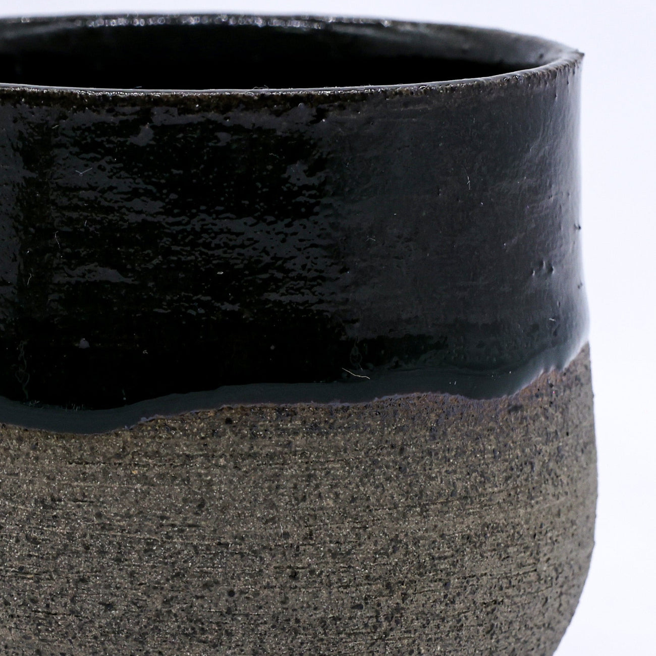 Black ceramic cup with textured base on a white background