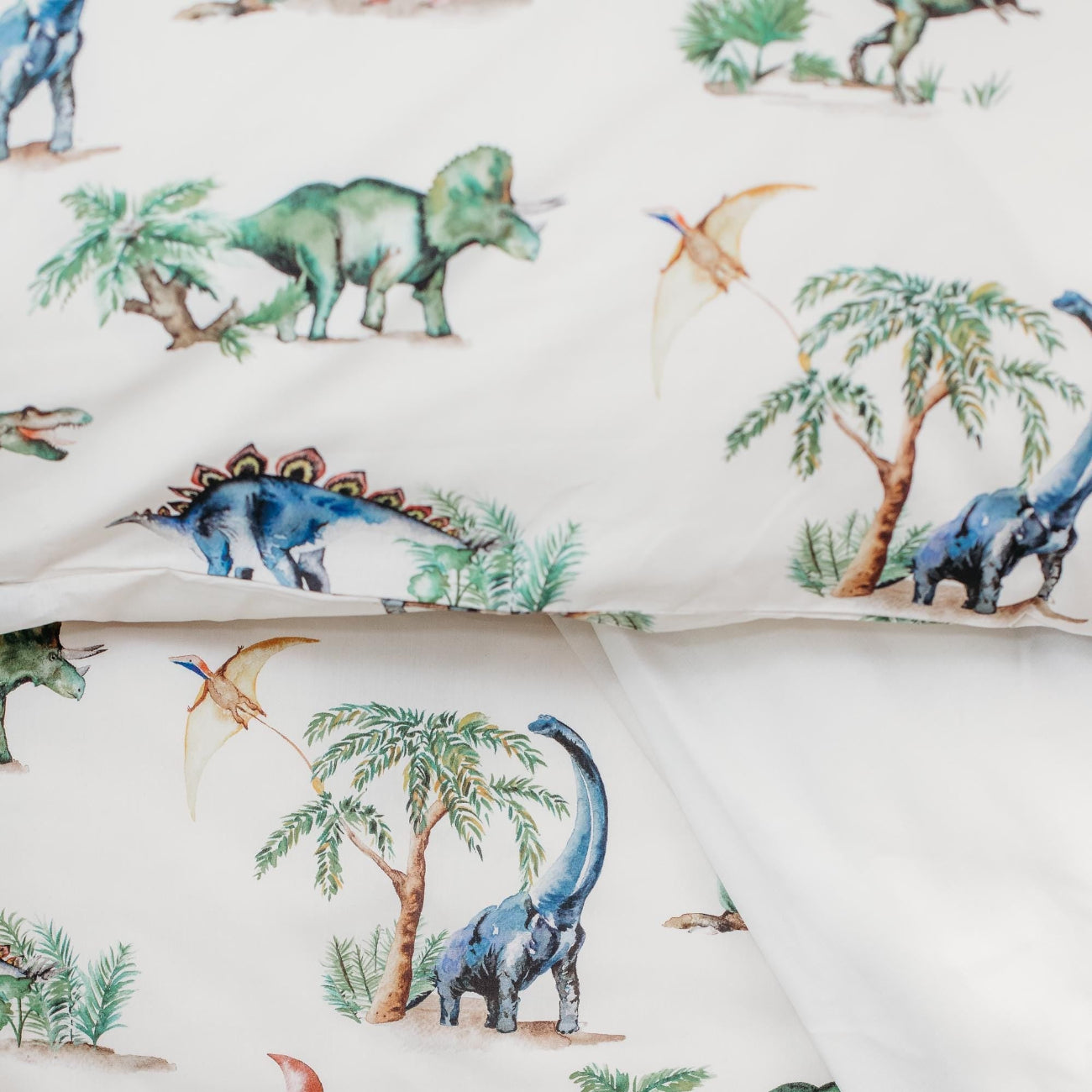 Dinosaur-themed fabric with various dinosaurs and trees on a white background