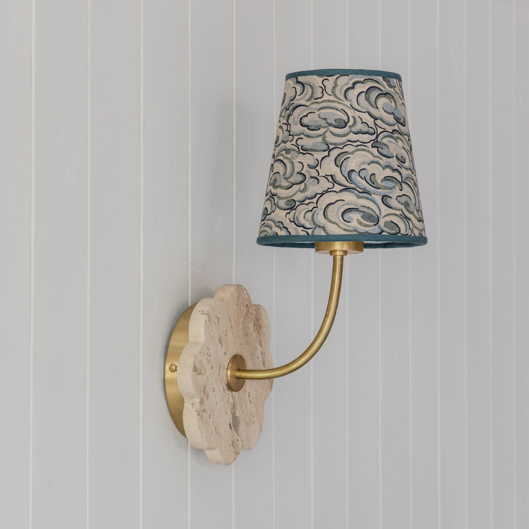 Wall-mounted lamp with decorative shade against a striped wall.