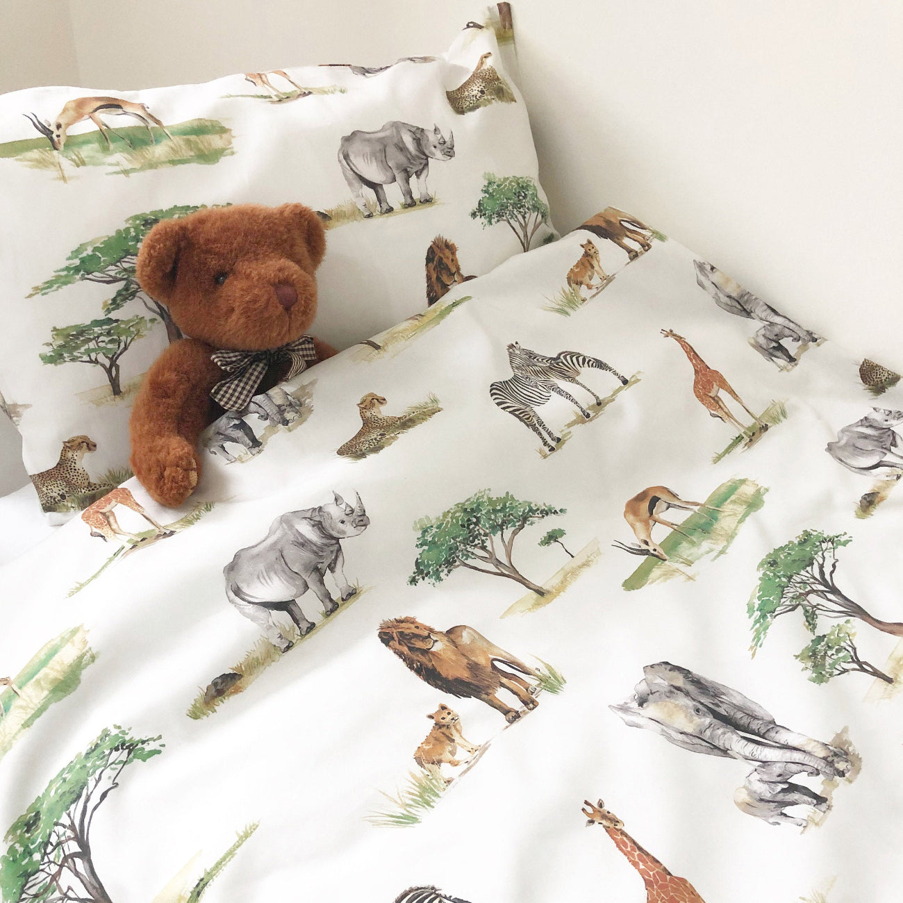 Children's bedding set with animal patterns and a teddy bear on a white background