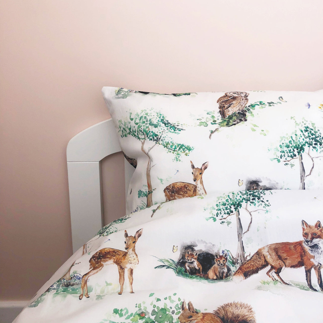 Bedding set with forest animals design on a bed against a beige wall.
