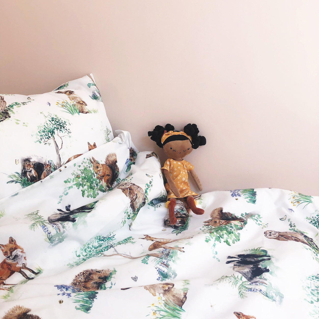 Children's bedding set with animal prints and a doll on a bed.