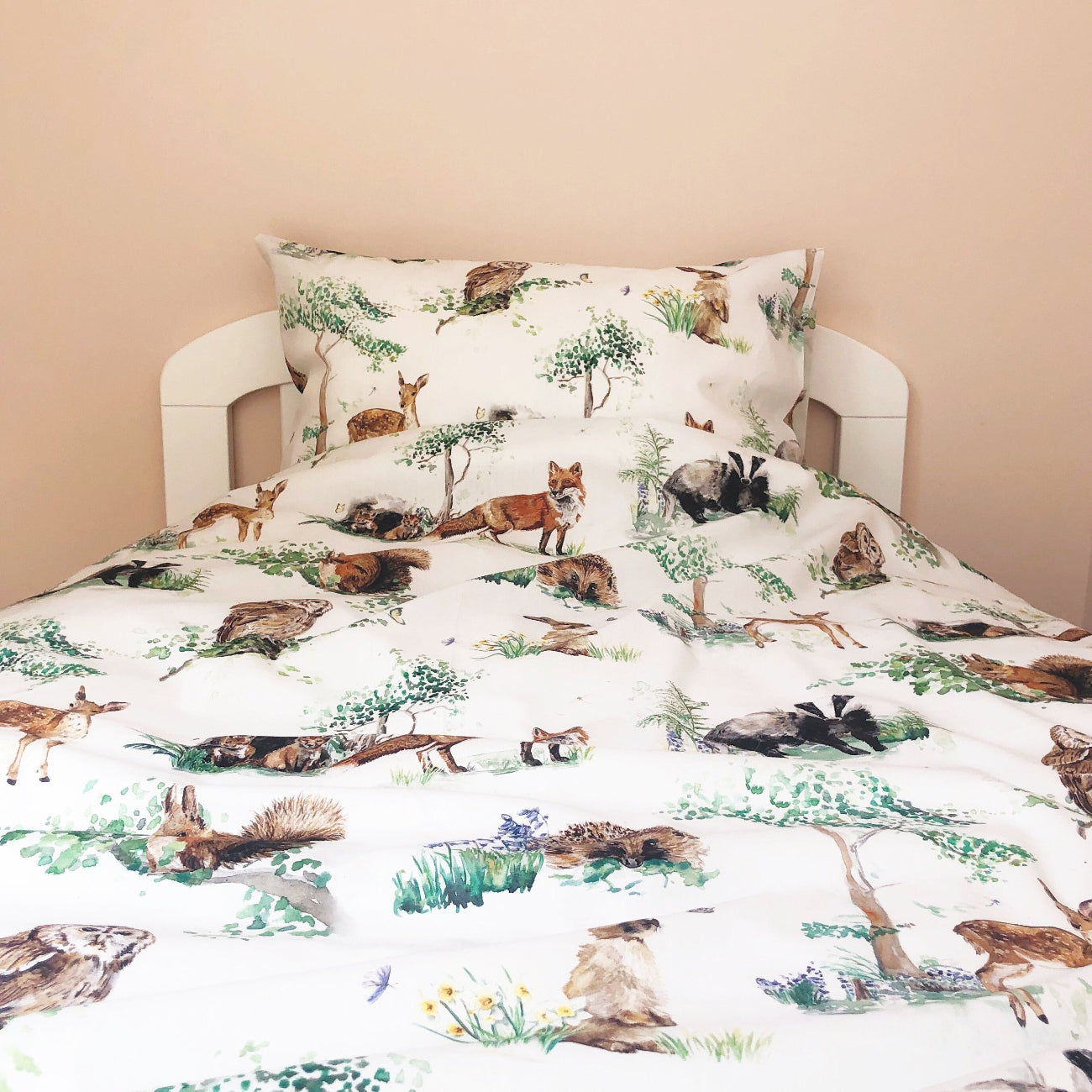 Bedding set with forest animal design on a bed against a beige wall.